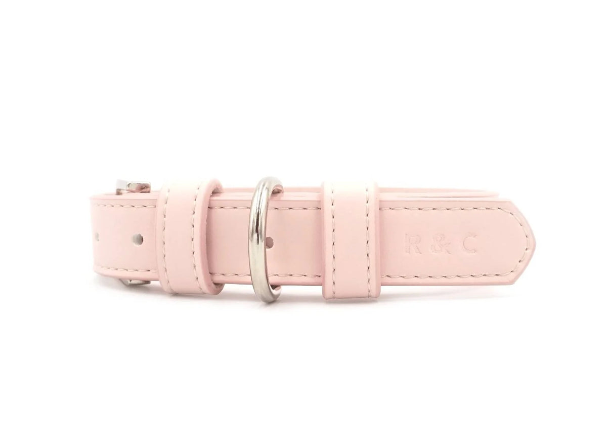 A light pink leather belt with silver-tone metal hardware, featuring an embossed 'R&C' logo on the tip, shown against a plain white background.