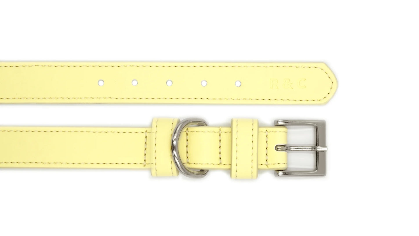 A pale yellow leather collar strap with silver-tone metal hardware, including a buckle, loop, and adjustment holes, shown on a plain white background.
